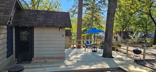 a shed with a table and a blue umbrella at #08 - One Bedroom Lakeview Cottage-Pet Friendly in Hot Springs