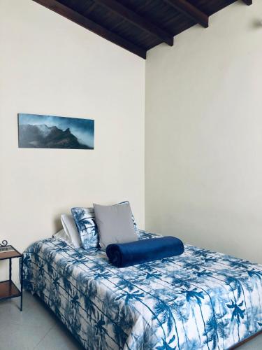 a bedroom with a bed with a blue pillow on it at HOTEL PLENITUD JARDÍN - Transporte, Tours y Más in Jardin