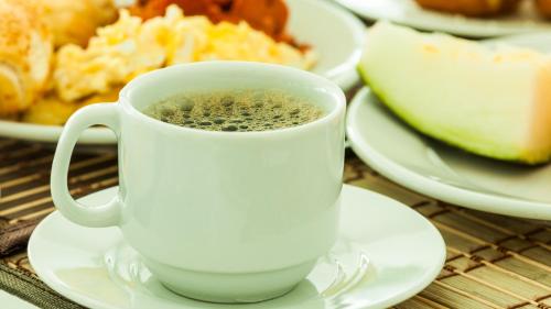 a cup of coffee sitting on a table with plates of food at Pousada Kalunga in Flecheiras