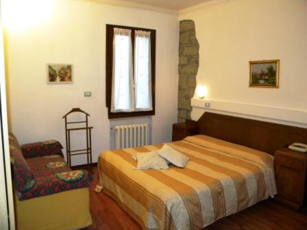 a bedroom with a bed and a chair and a window at Hotel del Corso in Sestola
