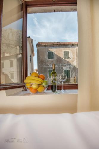 a window with a bowl of fruit and a bottle of wine at Hotel Rendez Vous in Kotor