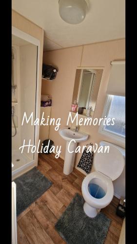 a bathroom with a toilet and a sink and a tub at Making Memories Holiday Caravan in Skegness