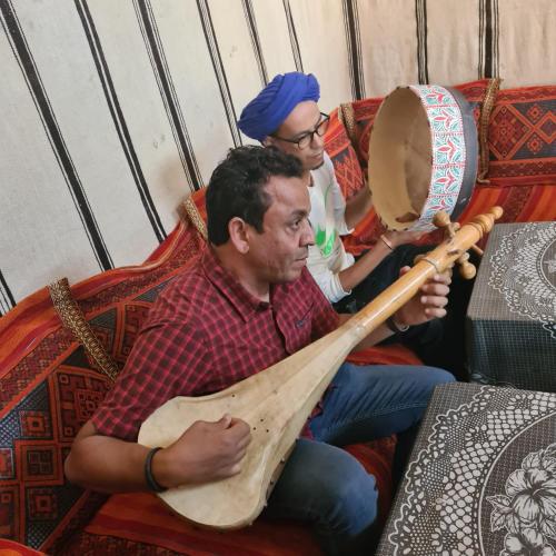 two men sitting on a couch playing a guitar at Ait Sedrate Tourism Cooperative Hotel in Boumalne
