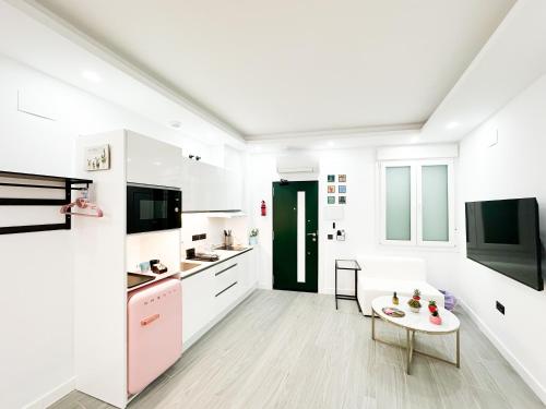 Una cocina blanca con una mesa y una puerta verde. en La Placita Boutique Trinidad, en Málaga