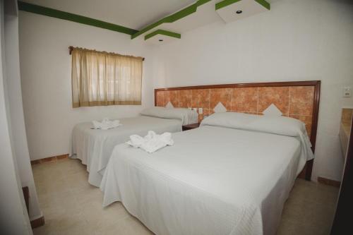two beds in a hotel room with white sheets at Nicte Ha Campeche in Campeche