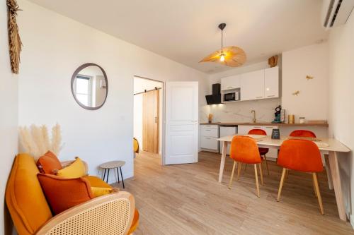 a living room and kitchen with orange chairs and a table at L'échappée de Chambord in Mont-près-Chambord
