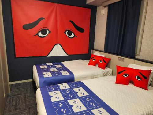 two beds in a room with a painting of a face at Henn na Hotel Fukuoka Hakata in Fukuoka