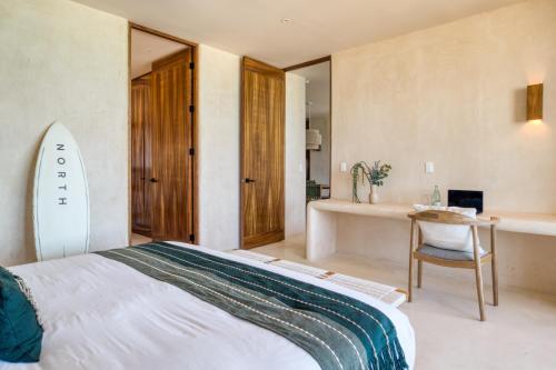 a bedroom with a bed and a desk and a surfboard at Amina Wind Resort by Tasman in Salinas