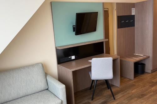 a living room with a chair and a tv at Garner Hotel Berlin - Charlottenburg, an IHG Hotel in Berlin