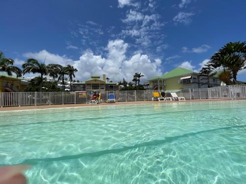 a swimming pool with blue water in front of a house at Ti'Masani in Saint-François