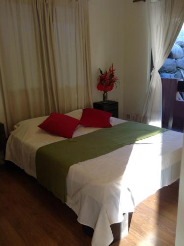 a bedroom with a large bed with red and green pillows at Royale attitude in Faaa