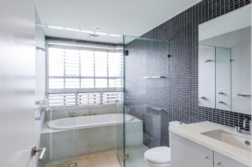 a bathroom with a glass shower and a toilet and a sink at Frida - Elysium in Noosa Heads