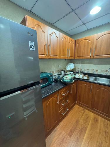 a kitchen with wooden cabinets and a stainless steel refrigerator at sand and beach haven at Ajman Corniche! in Dubai