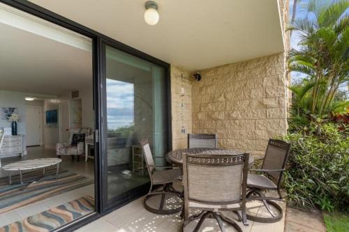 a patio with chairs and a table on a balcony at KIHEI BEACH, #109 condo in Kihei