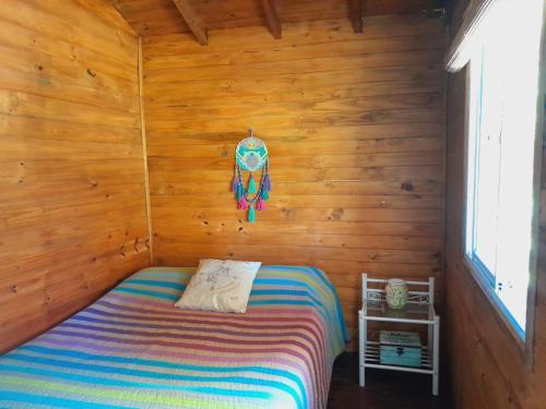 ein Schlafzimmer mit einem Bett in einer Holzhütte in der Unterkunft cabaña cuatro reinas in Tigre