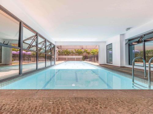 einen Pool in einem Gebäude mit großen Fenstern in der Unterkunft Flat em Hotel de Luxo MercPrivilege - 5 Min do Aeroporto in São Paulo