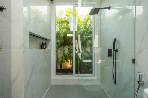 a bathroom with a glass shower with a window at Villa Casa Blanca, Bingin Beach in Uluwatu