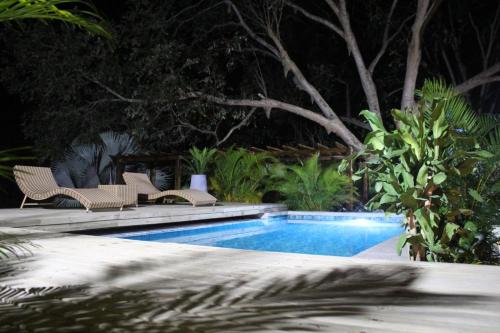 a swimming pool with two chairs next to at Río Celeste Poshtel Tayrona - Zaino in Calabazo