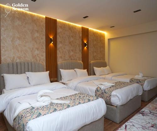 a hotel room with three beds with white sheets at Golden Season Hotel in Cairo