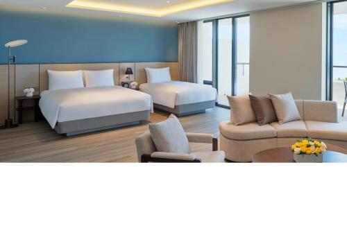a hotel room with two beds and a couch at Parnas Hotel Jeju in Seogwipo