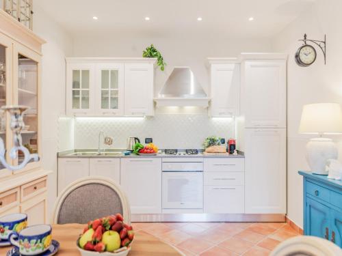 a kitchen with white cabinets and a table with a bowl of fruit at Apartment near Ostia Antica with Jacuzzi in Torvaianica