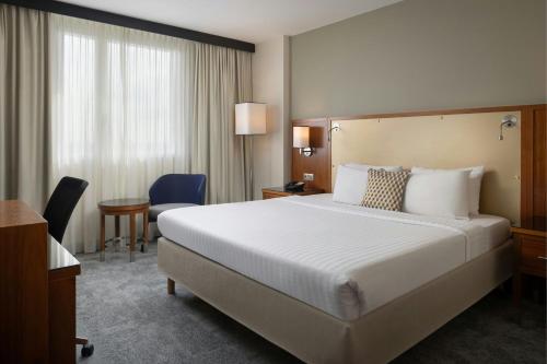 a hotel room with a large white bed and a table at Courtyard by Marriott Toulouse Airport in Toulouse