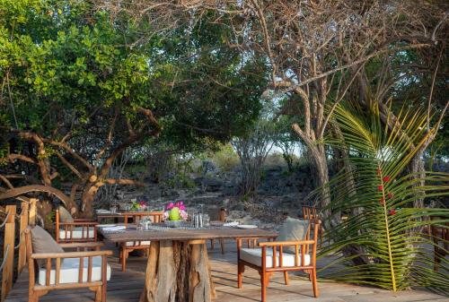 a wooden table and chairs on a patio with trees at The Kasa Malindi in Malindi