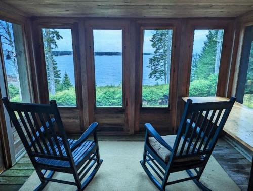 due sedie sedute su un portico che guarda fuori l'acqua di Oceanfront Crackling Cove Cottage Family firer pit slleeps 6 a Gouldsboro
