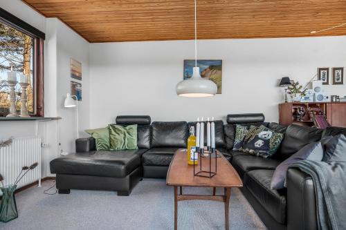 a living room with a black leather couch and a table at Cozy Holiday Home Near Lild Strand in Frøstrup