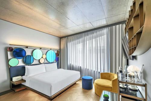 a bedroom with a white bed and a yellow chair at W Prague in Prague