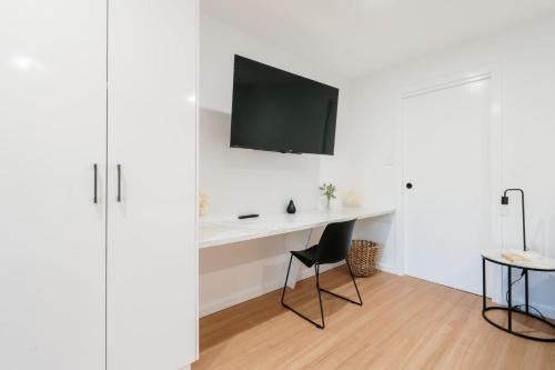 a room with a white desk with a tv on the wall at Tree Top Treasure Itas in Kings Meadows