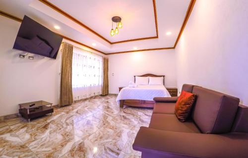 a bedroom with a bed and a couch and a tv at Villa Satu in Ráquira