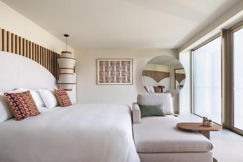 a bedroom with a white bed and a couch at Kimpton Atlantico Algarve by IHG in Albufeira