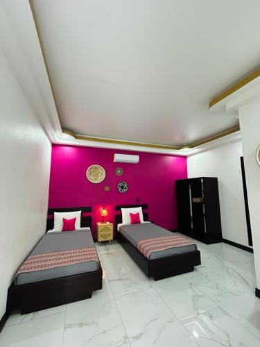 two beds in a room with a purple wall at Villa del Mar Hotel Boutique in Cahuita