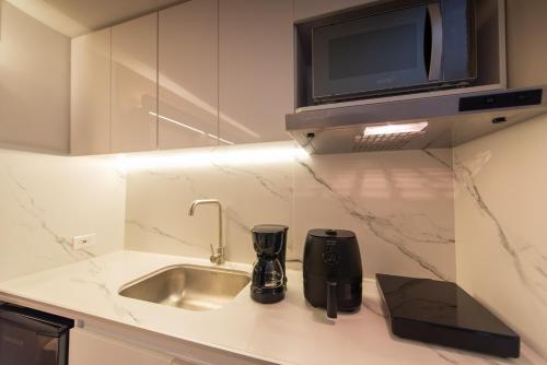 a kitchen counter with a sink and a microwave at Apart Suítes Stay Alhambra in Bogotá
