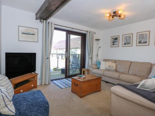 a living room with a couch and a tv at Hafan Bach - 233 Cae Du in Abersoch