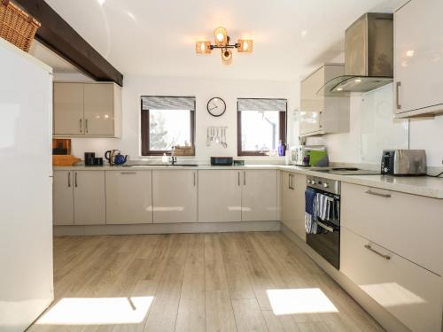 a kitchen with white cabinets and a stove top oven at Hafan Bach - 233 Cae Du in Abersoch