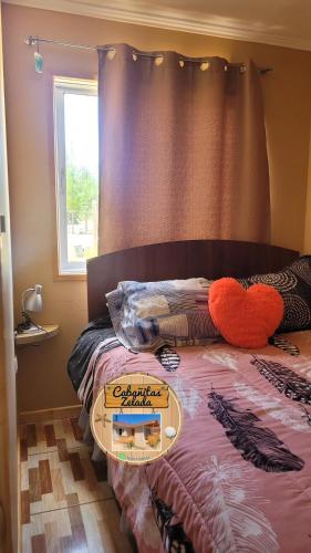 a bed with a heart pillow and a tray on it at Cabañitas Zelada in Algarrobo