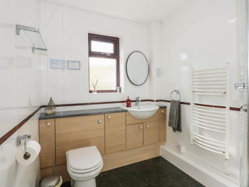 a white bathroom with a toilet and a sink at Hafan Bach - 233 Cae Du in Abersoch