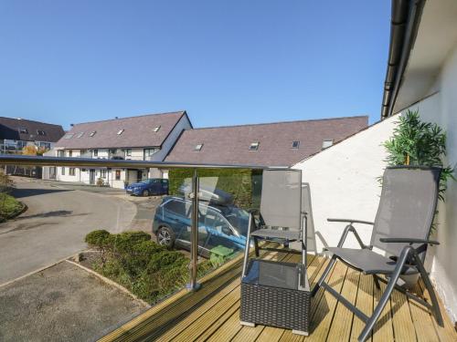 a balcony with two chairs and a car in a parking lot at Hafan Bach - 233 Cae Du in Abersoch