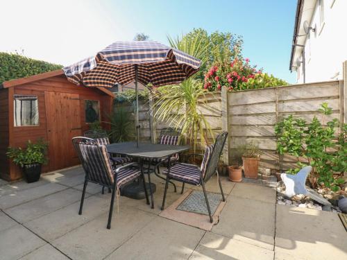 a table and chairs with an umbrella on a patio at Hafan Bach - 233 Cae Du in Abersoch