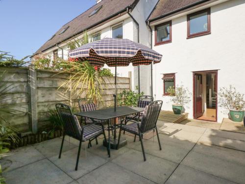 a table and chairs with an umbrella on a patio at Hafan Bach - 233 Cae Du in Abersoch