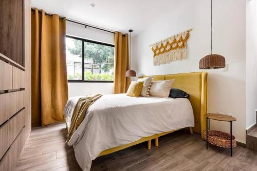 a bedroom with a bed with yellow curtains and a window at 4 - Loft Privado Cama King Size Roma Sur in Mexico City