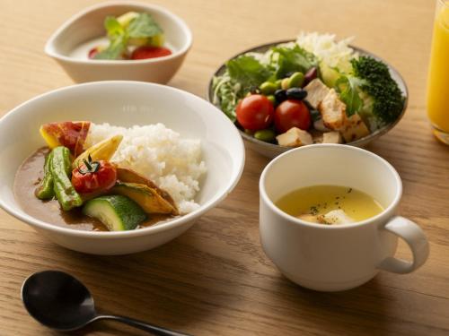 a table with bowls of food and a cup of coffee at Hotel SUI Kyoto Kiyomizu in Kyoto
