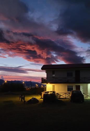 a house with two cars parked in front of a sunset at Cabañas Patagonia Encantada in Puerto Natales