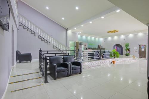 a waiting room with two chairs and a staircase at Airport Suites Hotel in Piarco