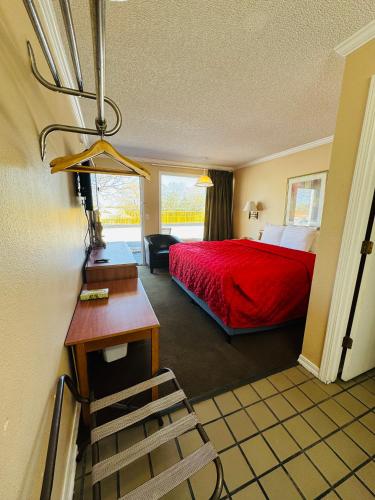 a hotel room with a red bed and a chair at Oak Grove Inn in Branson
