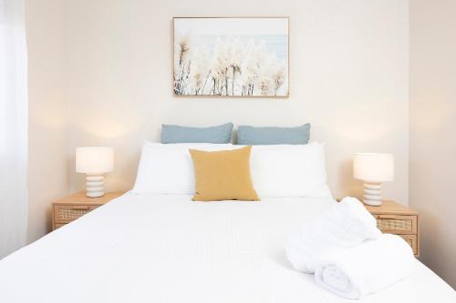 a bedroom with a white bed with two lamps at Bowling Greens in Tuncurry
