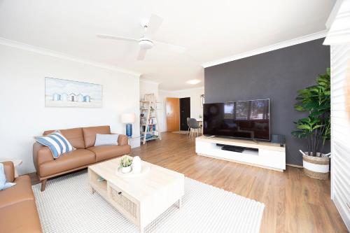 a living room with a couch and a flat screen tv at Bowling Greens in Tuncurry