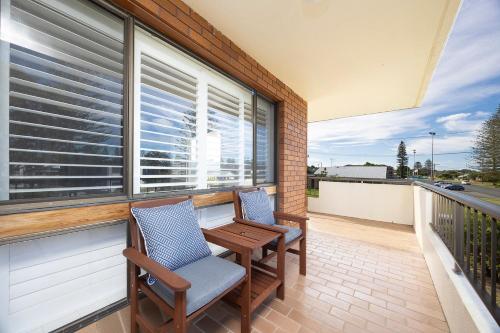 a balcony with two chairs and a table and a window at Bowling Greens in Tuncurry